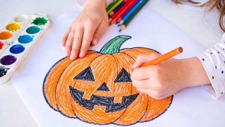 Bambino che disegna una zucca di Halloween