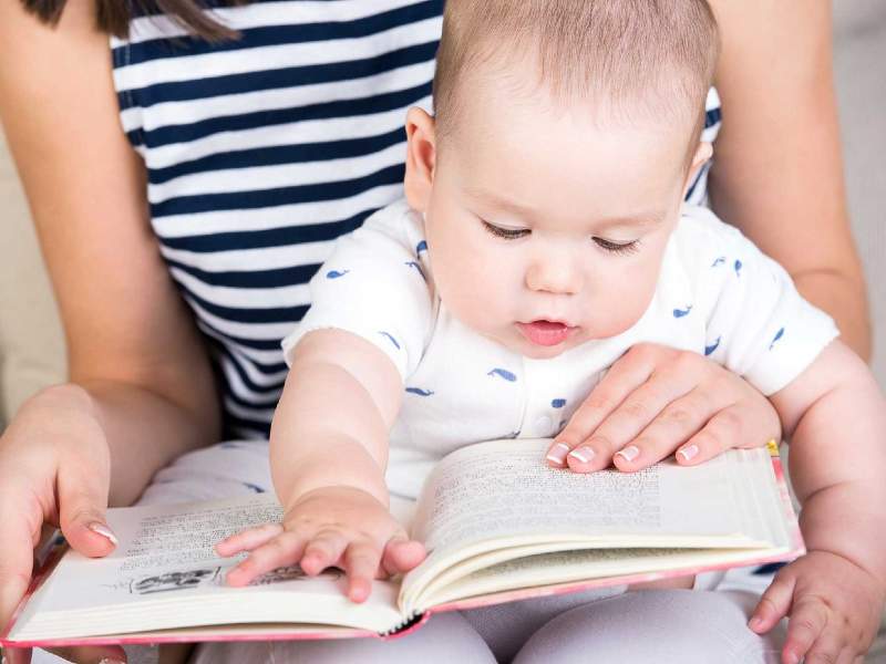 Neonato che guarda un libro