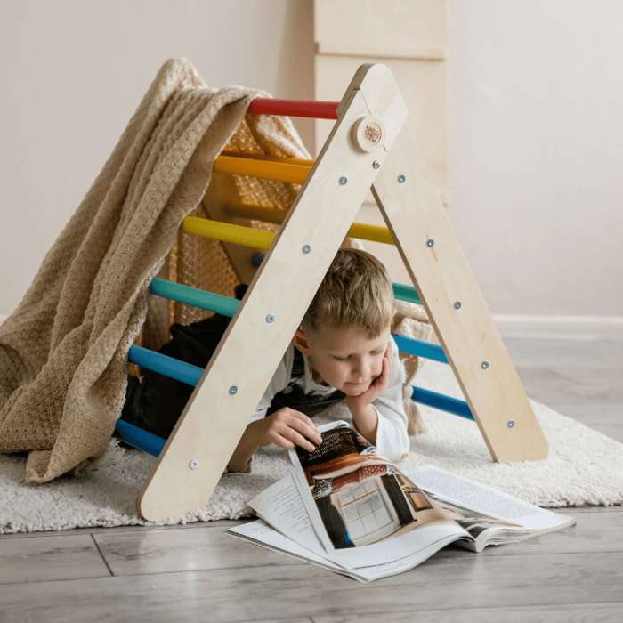 Bambino che legge sotto il triangolo di Pikler